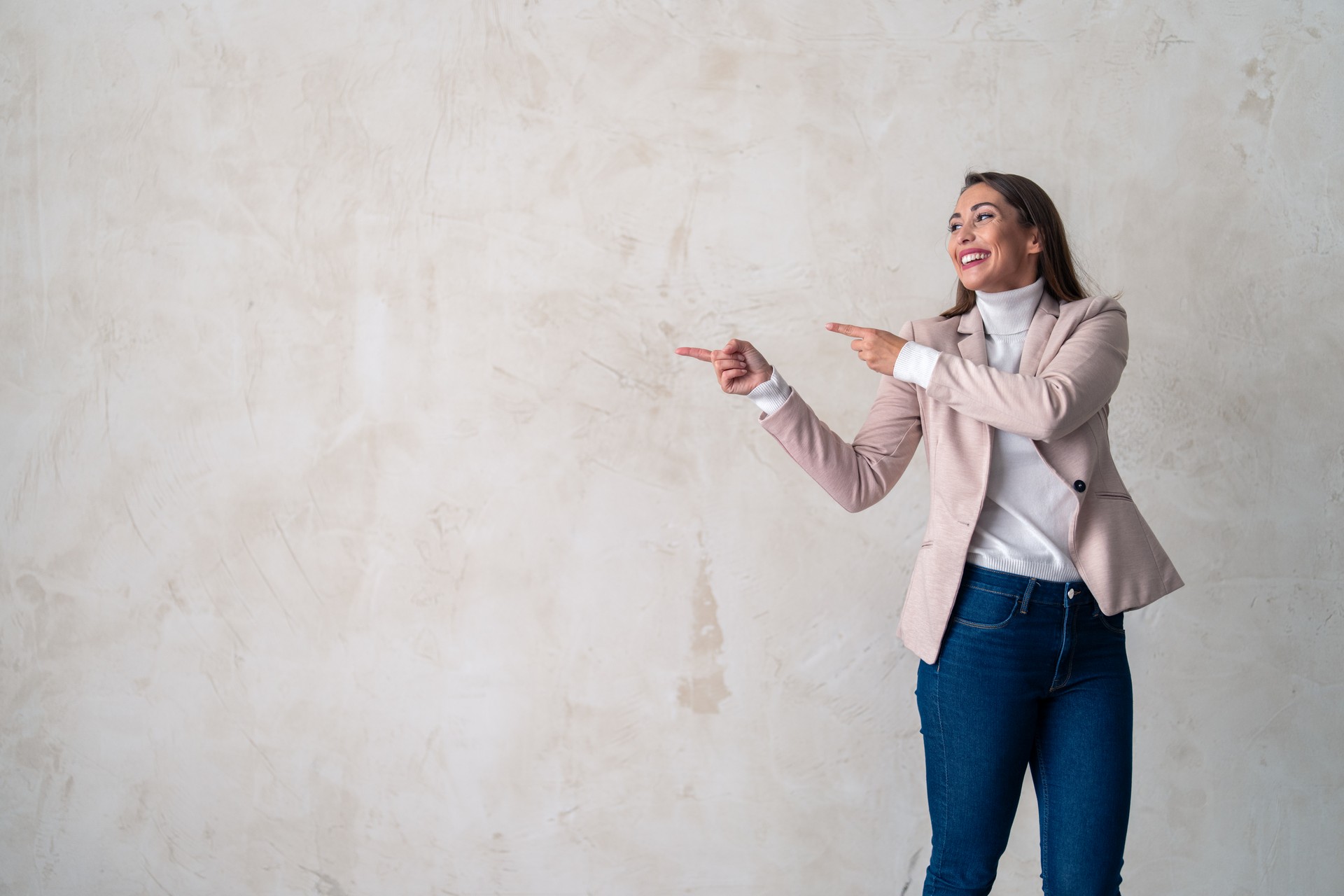 Portrait of confident smiling businesswoman pointing at copy space for advertising